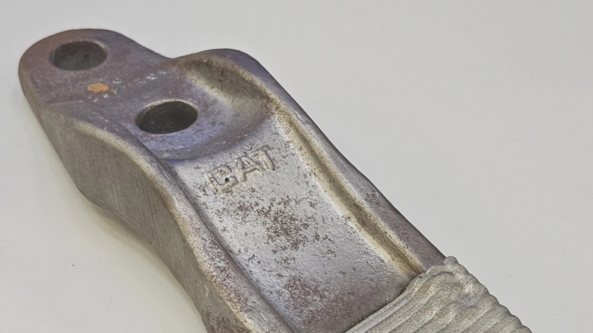 Imagen de una herramienta minera siendo reparada con tecnología láser, mostrando el proceso de deposición de material y la automatización del sistema AI-SLAM.