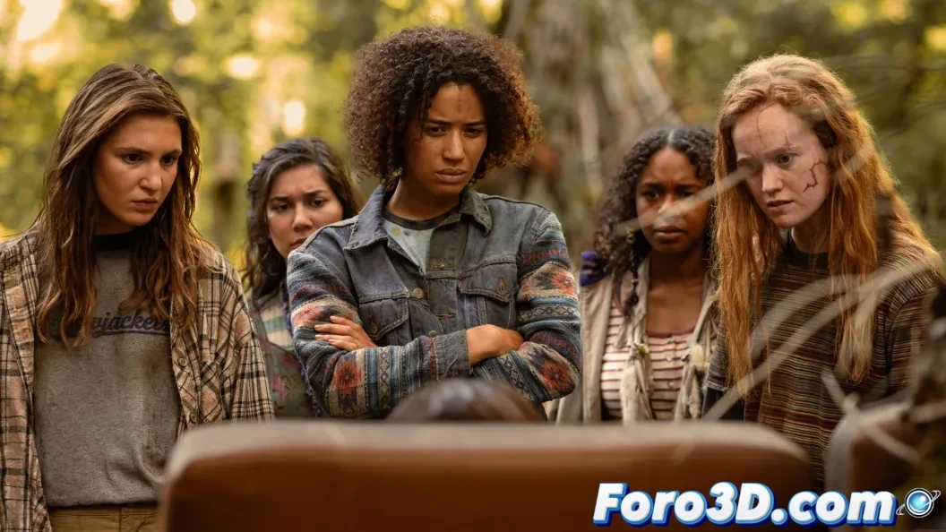 Grupo de jóvenes con máscaras primitivas persiguiendo a una chica vestida de blanco entre árboles nevados, con atmósfera oscura y tensa.
